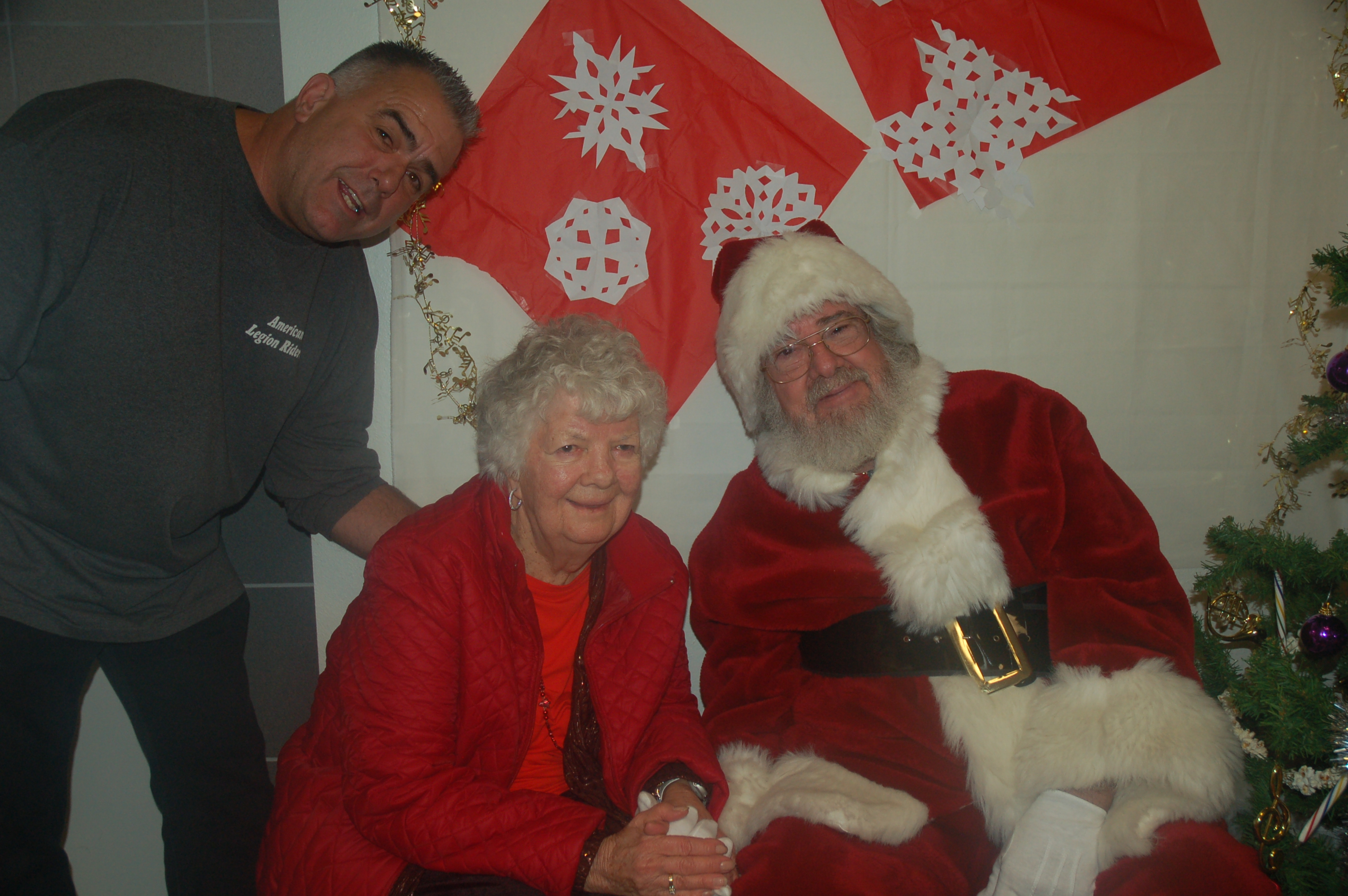 Elderly woman with Santa Claus and two men in a festive setting.