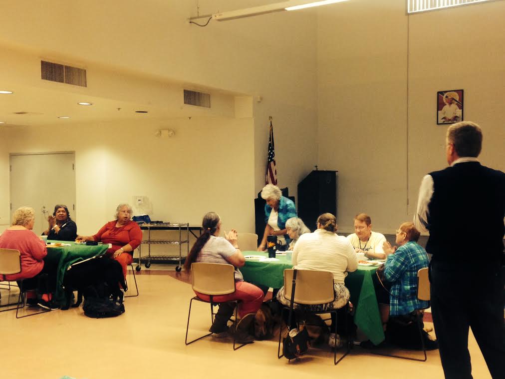 People gathered in a community room, engaging in conversation around tables.