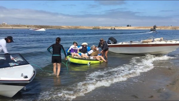People enjoying kayaking with assistance near the shore on a sunny day.