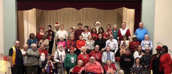 A group of elderly people and caregivers posing together for a festive photo.