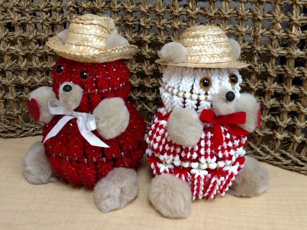 Two teddy bears wearing straw hats and checkered outfits sitting side by side.