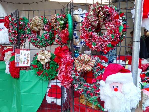 Colorful Christmas wreaths and decorations displayed for sale.