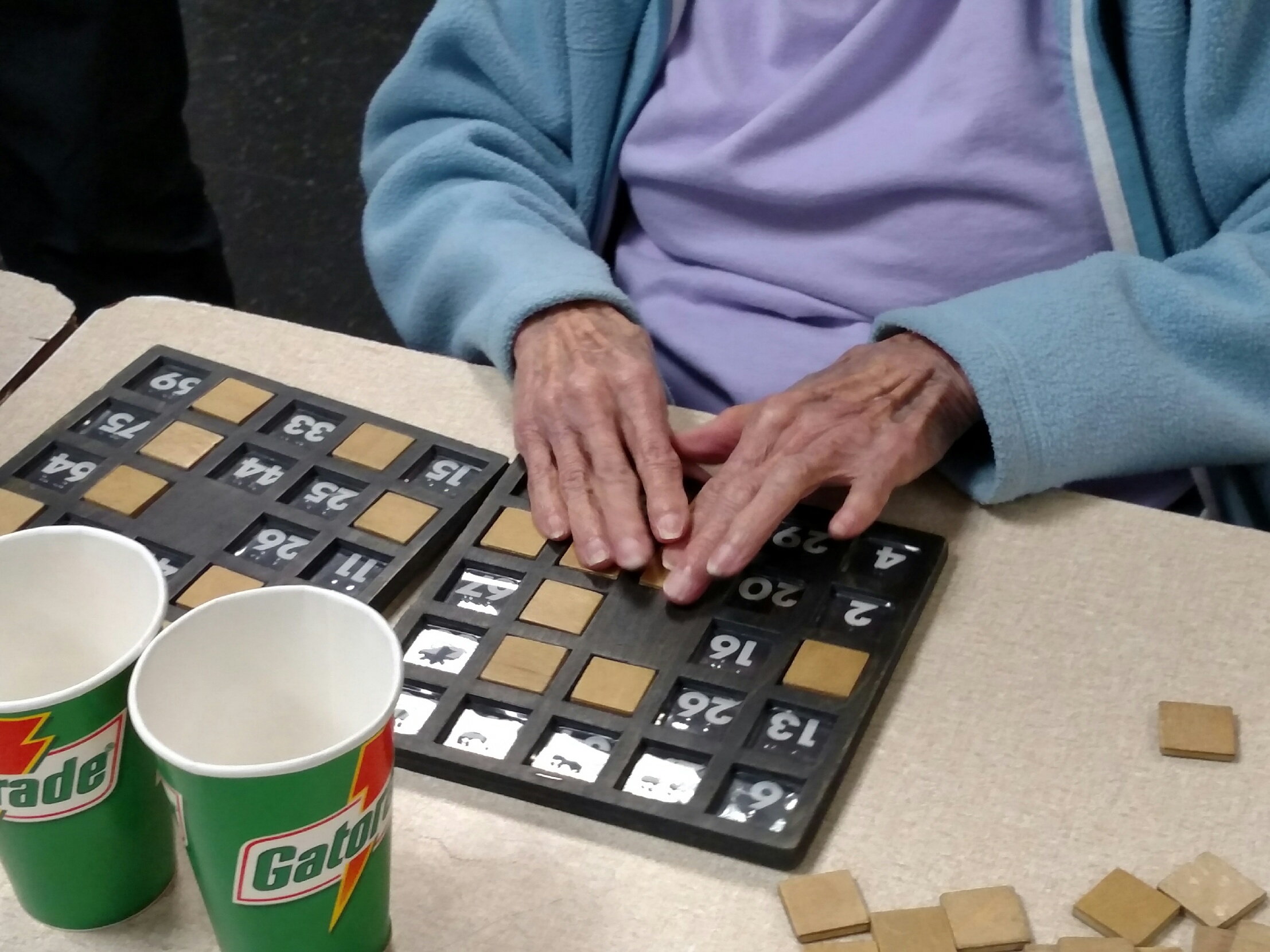An elderly person playing a word game with tiles.
