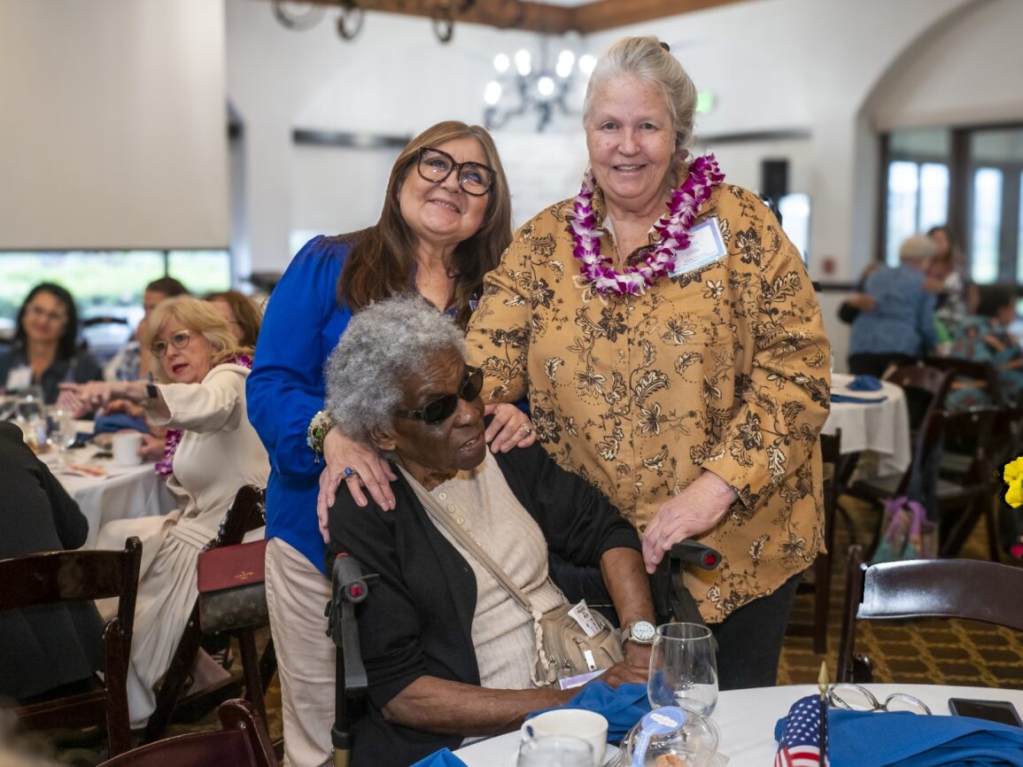 Three elderly women enjoying a social gathering indoors.