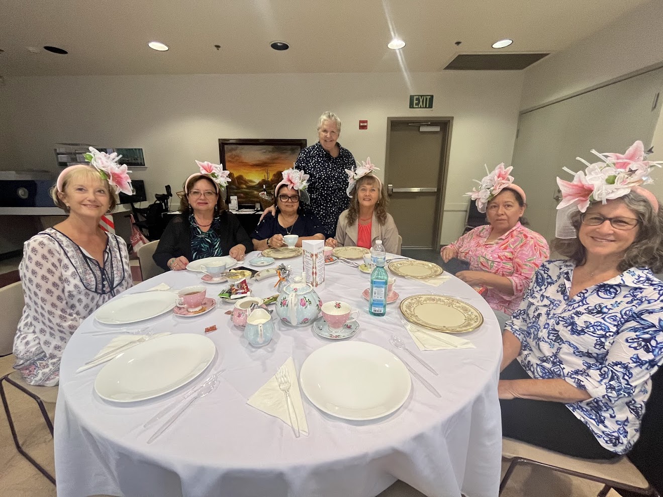 A group of elderly women and a man smiling around a decorated table.