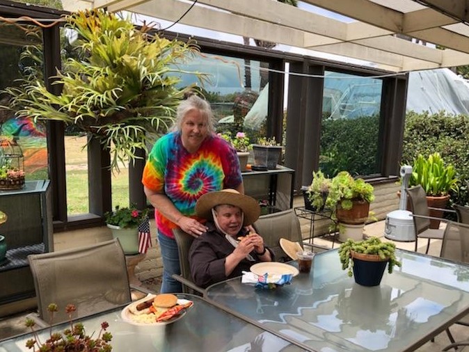 A cheerful elderly woman and a young boy enjoying a sunny meal outdoors.